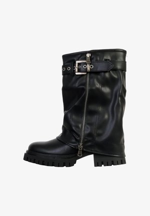 Botte noire montante en cuir synthétique avec une fermeture éclair latérale, une sangle à boucle réglable et une semelle à crampons épaisse pour une meilleure adhérence.