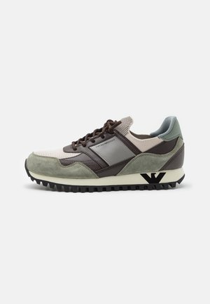 Low-top sneaker med blandet grøn ruskind, brun læder og beige strikstof med sorte snørebånd og sort logo på den beige sål.