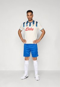 Fotbollströja med vit bas och blå vertikala ränder samt "Lete"-logotyp, kombinerad med blå shorts och vita strumpor.