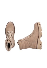 Bottines en suède beige avec doublure en fourrure, devant lacé, côtés rembourrés et semelles en caoutchouc robustes avec des crampons prononcés.