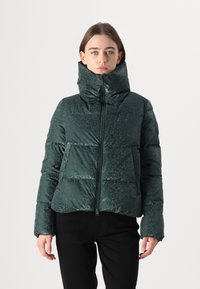 Groene pufferjack met hoge kraag, glanzende afwerking en ritssluitingen. Beschikt over zijzakken en een bovenste patroon.