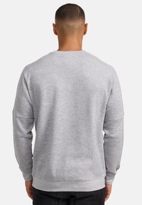 Szary sweatshirt z długimi rękawami, okrągłym dekoltem i ściągaczami. Charakteryzuje się teksturowanym materiałem i luźnym krojem z dołem, który opada na talii.