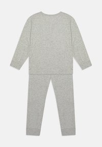 Ensemble de loungewear deux pièces gris clair comprenant un haut à manches longues et un pantalon assorti. Fabriqué en tissu doux et texturé avec des poignets côtelés.