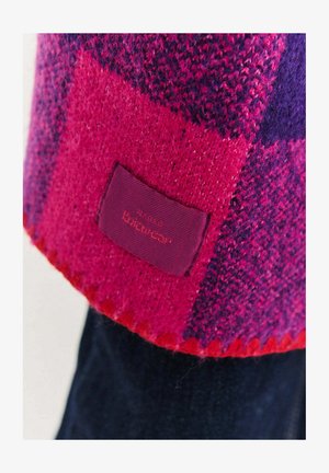 Dzianinowy szalik w żywym różowo-fioletowym wzorze w kratę. Miękka faktura z przeszytym brzegiem i przymocowaną prostokątną metką z tkaniny.