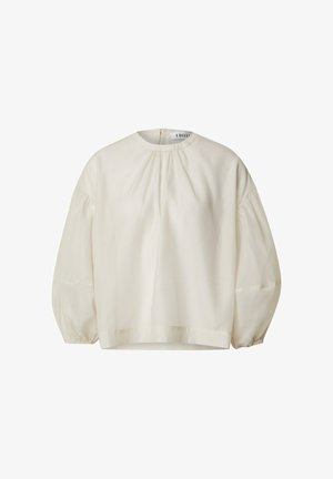 Hellbeige Bluse mit hochgeschlossenem, rundem Ausschnitt und langen Puffärmeln. Mit gerafften Details an den Schultern und einem geraden Saum.