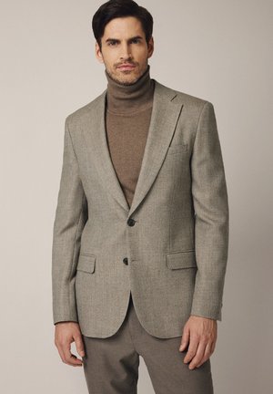 Szary blazer o fakturowanym materiale, z dwoma guzikami, w połączeniu z brązowym golfem. Posiada kieszenie z klapami i klapy w kształcie notcha. Gładki materiał.