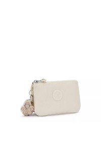 Portafoglio beige con zip realizzato in morbido tessuto, caratterizzato da un logo rotondo e un piccolo charm in peluche attaccato alla zip per un tocco di dettaglio in più.