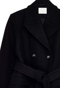 Mustast villa segust topeltlõikelise mantliga, millel on laiad tõmblapid, ees taskud ja sobiv vöö. Tekstuuriga kangas, siledad nööbid ja lõigatud sobivus.