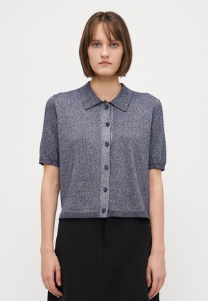 Short-sleeve, collared knit cardigan in navy with a speckled texture. Features a button front and ribbed hem, paired with a black skirt.