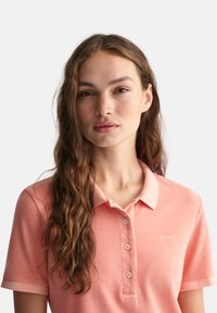 Polo T-shirt i lyserød bomuld med en blød tekstur, der har krave, korte ærmer og en fem-knaps stolpe. Logo broderet på brystet.