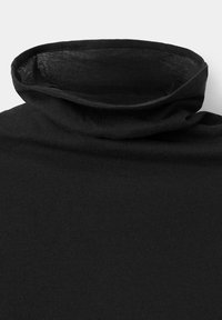 Black turtleneck shirt collar folded over, showing soft fabric texture on a plain light background.