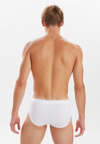 Hvide bomuldsunderbukser med en glat tekstur, elastisk talje, og ingen synlige mønstre, vist fra ryggen.