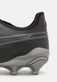 Botas de fútbol negras con parte superior de cuero texturizado, detalles en gris y un diseño elegante. Cuenta con tacos moldeados y una suela de goma duradera.