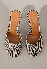 Sandales à glissière à imprimé zèbre avec une tige douce et texturée et une semelle intérieure en cuir marron. Bout ouvert arrondi avec un design à large bride.