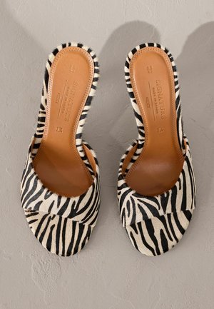 Sandales à glissière à imprimé zèbre avec une tige douce et texturée et une semelle intérieure en cuir marron. Bout ouvert arrondi avec un design à large bride.