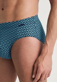 Blauwe en teal gestreepte zwembroek met een geometrisch driehoekenpatroon, gemaakt van rekbaar materiaal met een comfortabele tailleband.