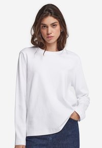 Witte lange mouw shirt met een ronde hals, gemaakt van zacht katoen. Beschikt over een comfortabele pasvorm en rechte zoom. G gedragen met een spijkerrok.