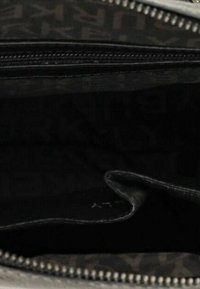 Sac en tissu noir ouvert avec une poche intérieure visible, fermeture éclair métallique partiellement zippée et doublure à motif sombre.