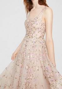 Vestido bordado en tejido transparente, con patrones florales en colores pastel. Tirantes finos, con un corsé ajustado y una falda fluida.