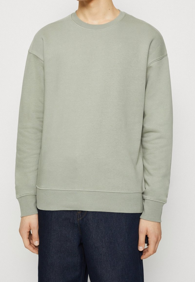 Lichtgroene sweatshirt met een ronde hals, lange mouwen en geribbelde boorden. Gladde textuur, casual pasvorm, gecombineerd met donkere jeans.