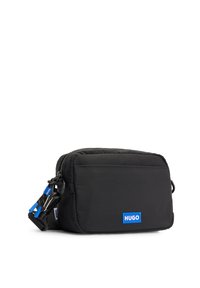Bolso de hombro negro de nailon con forma rectangular, cierre de cremallera y logo azul "HUGO". Superficie texturizada con correa ajustable y detalles metálicos.