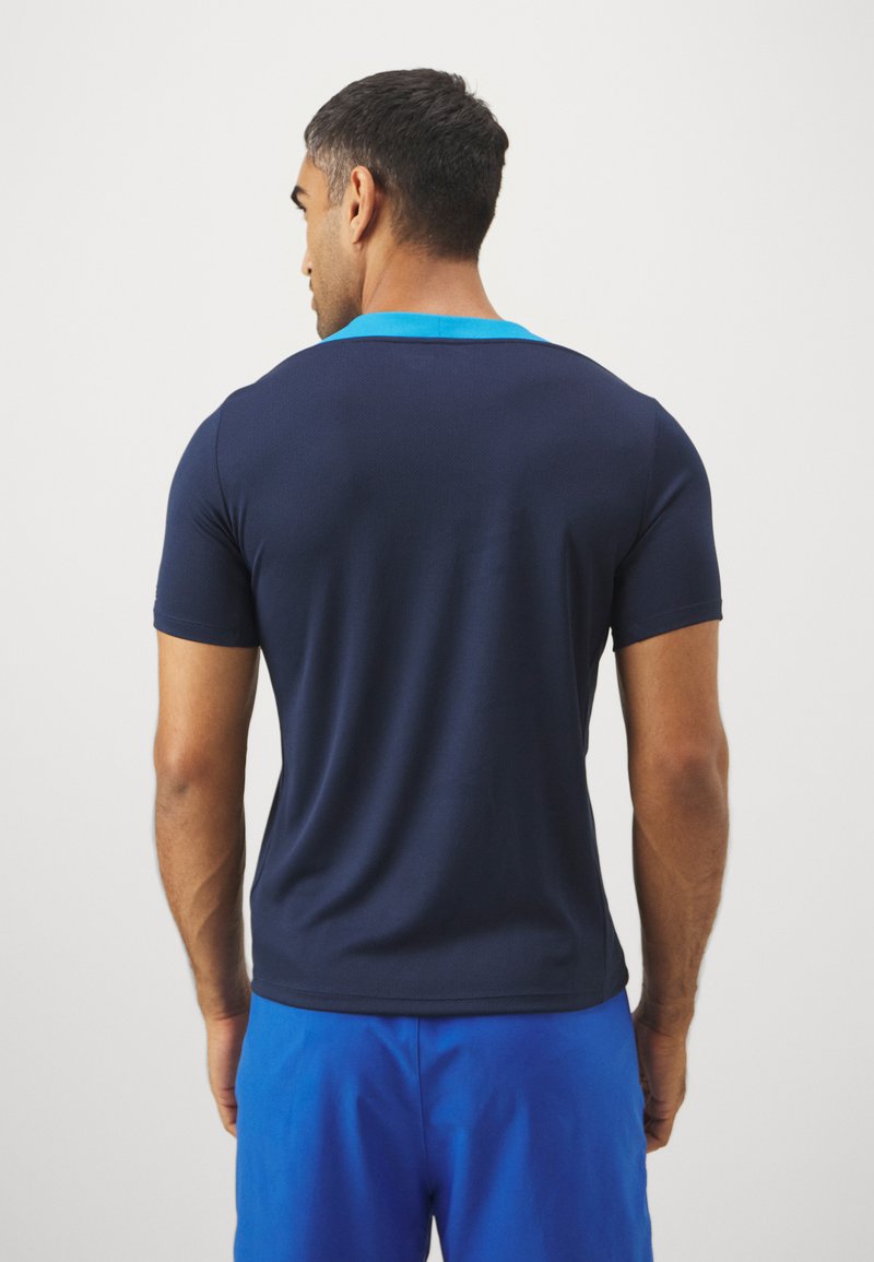 Granatowa koszulka sportowa z krótkim rękawem, z kontrastowym jasnoniebieskim kołnierzykiem, gładką teksturą i dopasowanym krojem.