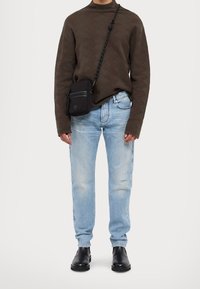 Dark brown textured sweater, light blue distressed jeans, black crossbody bag with zippers, and black ankle boots.