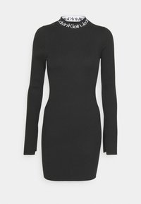Zwarte geribde lange mouwen jurk met een slank silhouet. Heeft een witte logoband bij de kraag voor contrast. Gladde textuur en minimaal ontwerp.