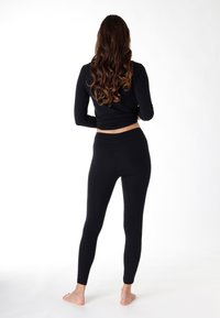 Top nero a maniche lunghe e leggings realizzati in materiale elastico, design aderente, texture morbida, con una silhouette pulita e slanciata.