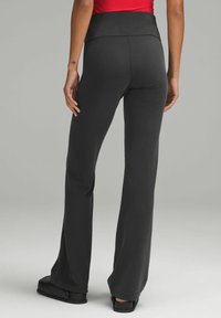 Mustat ribbitetyyliset leveälahkeiset housut, joissa on korkea vyötärö, tekstuuripinta ja rento istuvuus, yhdistettynä mustiin liukuvien kenkien kanssa.