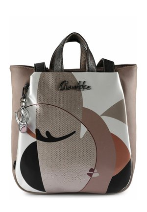 Rucksack mit abstraktem Gesichtsmotiv in Beige, Braun, Schwarz und Weiß, mit strukturierten Punkten, schwarzen Griffen und einem daran befestigten Logozier.