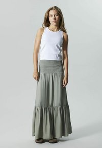 Weißes Tanktop kombiniert mit einem langen, hellgrünen Rock mit einem gerafften Oberteil und mehreren Rüschenschichten am Saum. Weicher Stoff, lässiges Design.