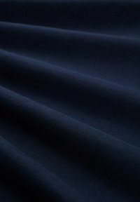 Tejido de textura azul oscuro con superficie suave y lisa; presenta sutiles ondulaciones y pliegues, lo que indica que es un material ligero apto para diversas aplicaciones.