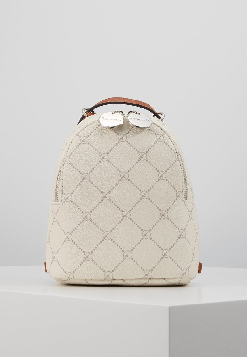 Petit sac à dos beige avec motif en losange, logos circulaires, poignée supérieure marron et doubles tirettes de fermeture éclair argentées avec le nom de la marque.