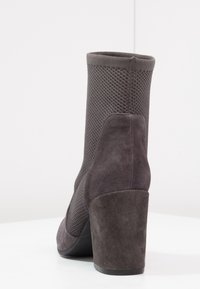 Botki w ciemnoszarym zamszu z siateczkowymi wstawkami, zaokrąglonym noskiem i słupkowym obcasem. Teksturowana tkanina i bezszwowy design wierzchu.