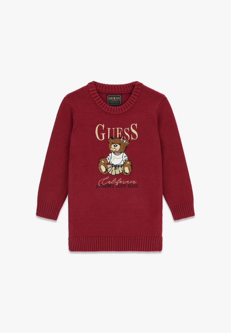 Pull rouge pour enfants avec col et poignets côtelés, représentant un ours en peluche portant une jupe et le texte "Guess California Authentic Denim Brand."
