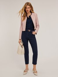 Rosa kort jacka över en marinblå ribbad topp, kombinerad med marinblå byxor och beige slingback-klackar. En krämfärgad väska med dragsnöre fulländar looken.