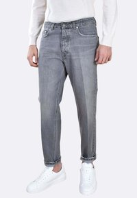 Jeans in denim grigio con fit dritto, caratterizzati da dettagli sbiaditi, cinque tasche e orlo arrotolato. Abbinati a sneakers bianche.