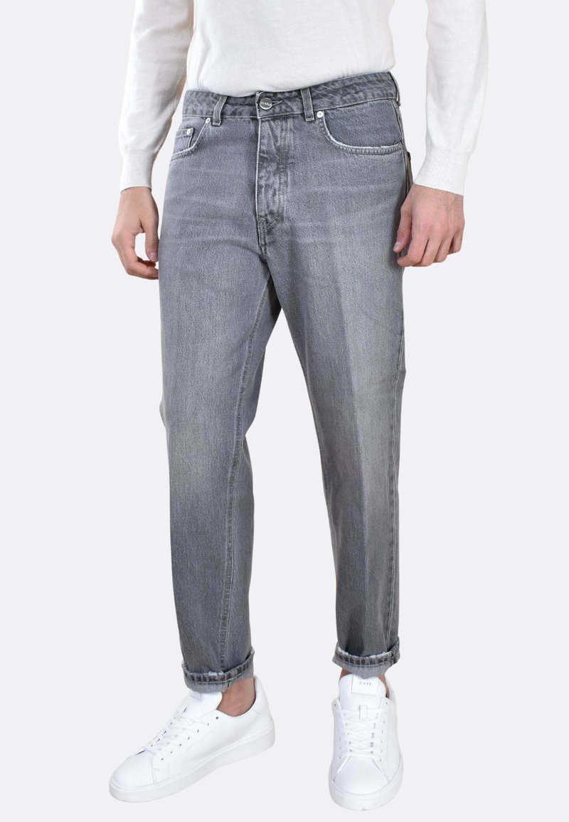 Jeans in denim grigio con fit dritto, caratterizzati da dettagli sbiaditi, cinque tasche e orlo arrotolato. Abbinati a sneakers bianche.