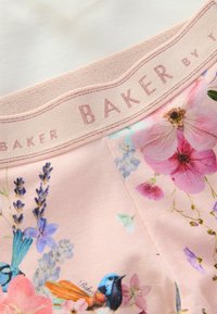 Vêtement rose pâle avec un imprimé floral comprenant des oiseaux bleus et diverses fleurs. Tissu doux avec une taille texturée étiquetée "BAKER."