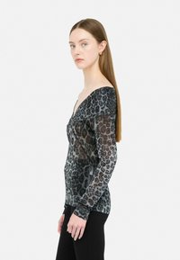 Langärmliges Oberteil mit Leopardenmuster in Schwarz und Grau mit schimmerndem Finish, ausgestattet mit einem tiefen V-Ausschnitt und taillierter Silhouette. Weicher, dehnbarer Stoff.