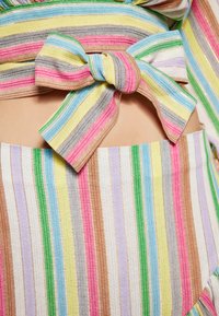 Tessuto a righe multicolore con linee orizzontali in rosa, blu, verde, giallo e marrone, con un dettaglio di fiocco annodato e una superficie liscia.