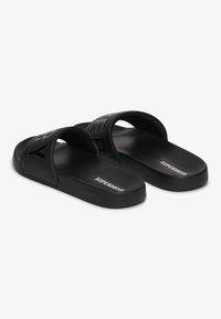 Infradito neri con due fasce larghe. La fascia superiore presenta la scritta in rilievo "SUPERDRY". Suole texturizzate per aderenza e comfort.
