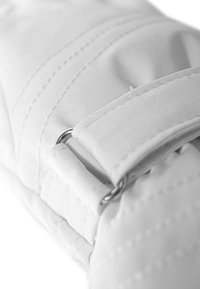 White fabric with a quilted texture, featuring stitched lines and a metal D-ring attachment, indicating a functional design.