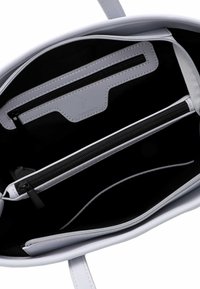 Vit syntetisk handväska inuti, med svart foder, två dragkedjefickor och släta, sydda kanter.