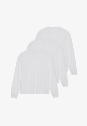 Trois t-shirts blancs à manches longues en tissu léger. Ils ont un col rond et des manches longues ajustées avec des poignets ourlés.