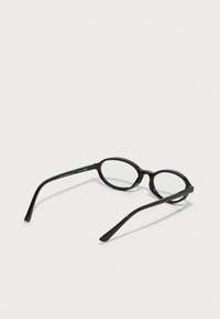 Ochelari ovali negri cu lentile clare. Au un cadru din plastic neted și brațe subțiri, cu o marcaj subtil pe una dintre brațe.