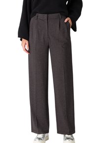 Pantalons larges gris charbon avec plis, fabriqués à partir d'un tissu texturé. Présente une taille ajustée et des poches latérales, stylés avec des chaussures argentées.