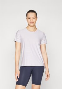 Maglietta corta a maniche concollo rotondo di un leggero color lavanda, con una trama liscia e una vestibilità comoda, abbinata a pantaloni ciclisti blu navy.
