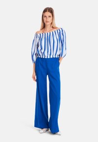 Off-the-shoulder striped top in blue and white, paired with wide-leg blue pants. Lightweight fabric with elastic waistband and puffed sleeves.